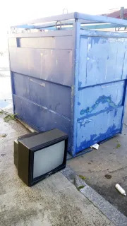 Televisor abandonado junto a un contenedor de papel en Cuéllar